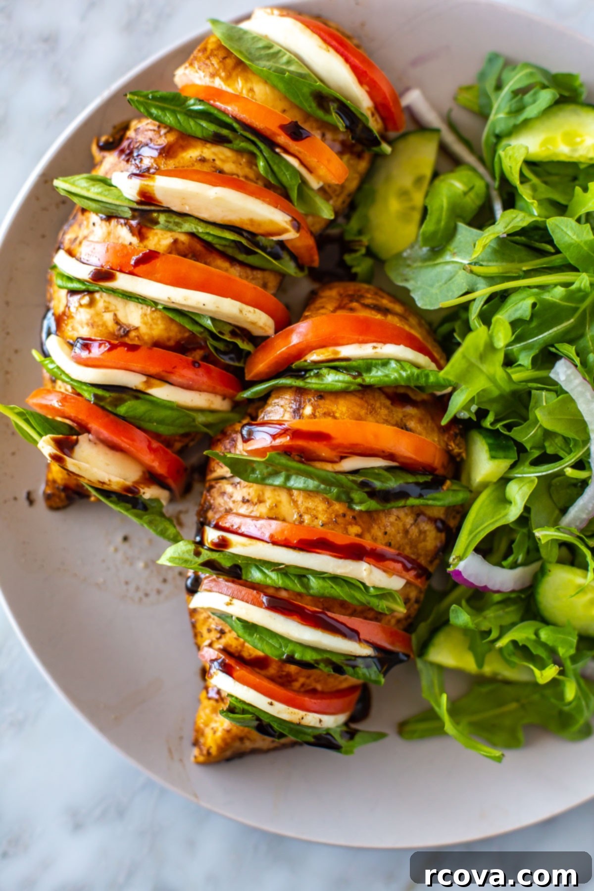 Caprese Hasselback Chicken Bake 6 Close-up of baked Hasselback Caprese Chicken, revealing the stuffed layers of mozzarella, tomato, and basil, served with a fresh salad.