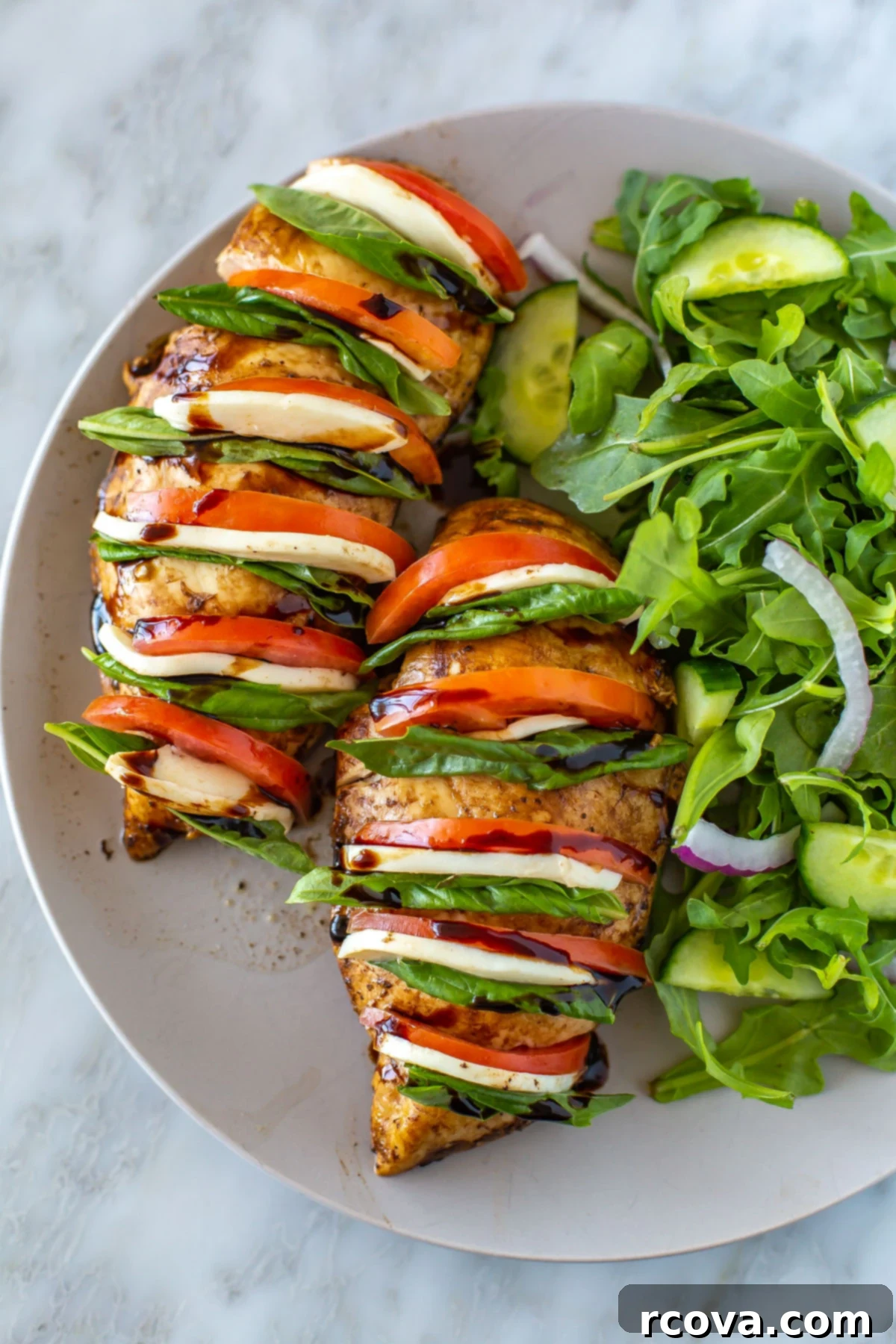 Caprese Hasselback Chicken Bake 8 Close-up of baked Hasselback Caprese Chicken, revealing the stuffed layers of mozzarella, tomato, and basil, served with a fresh salad.
