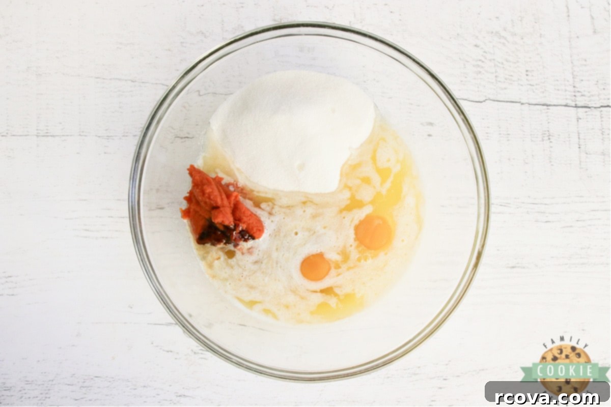 Sweet Glazed Pumpkin Oat Delights 8 Wet ingredients including melted butter, pumpkin puree, sugar, molasses, vanilla, and eggs being whisked together in a bowl.