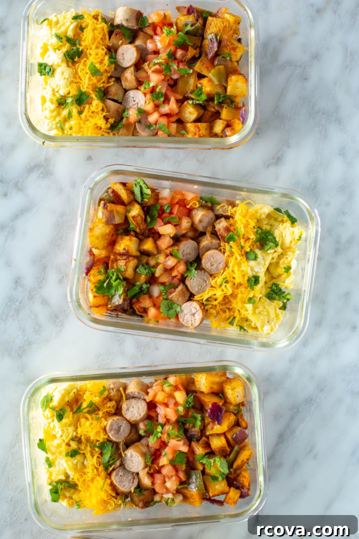 Fuel Your Mornings: Healthy Breakfast Prep 14 Three meal prep containers, each filled with roasted vegetables, scrambled eggs, and cooked sausage.