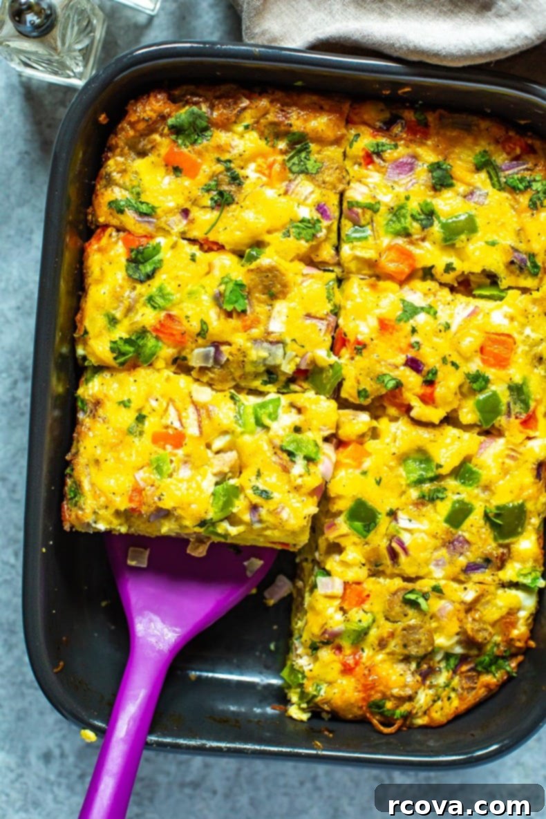 Fuel Your Mornings: Healthy Breakfast Prep 34 A cooked sausage hashbrown breakfast casserole in a black casserole dish cut into 8 pieces with a spatula picking up a piece.