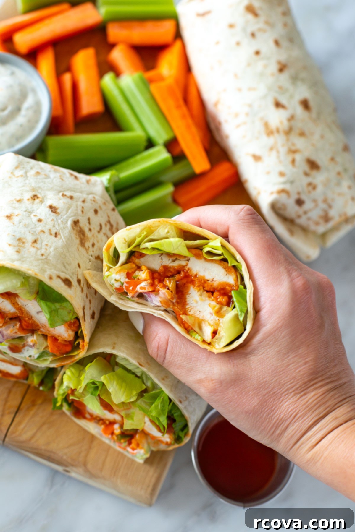 Ultimate Buffalo Chicken Wraps 9 Hand holding a crunchy buffalo chicken wrap, with a bite taken out to show the layers.