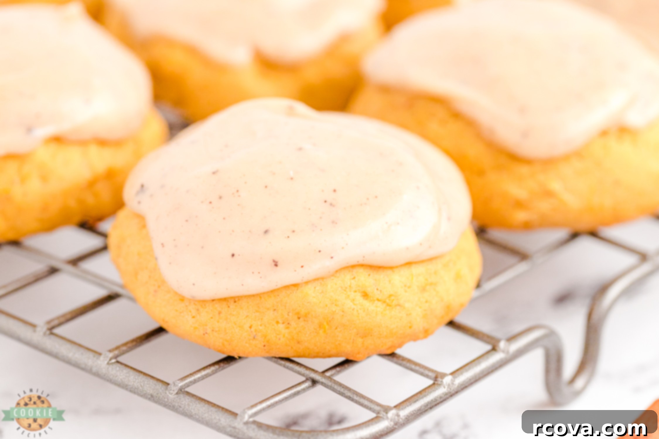 Spiced Frosted Pumpkin Ginger Cookies 2 A single frosted pumpkin ginger cookie resting on a wire cooling rack, showcasing its inviting golden-brown hue and creamy frosting.