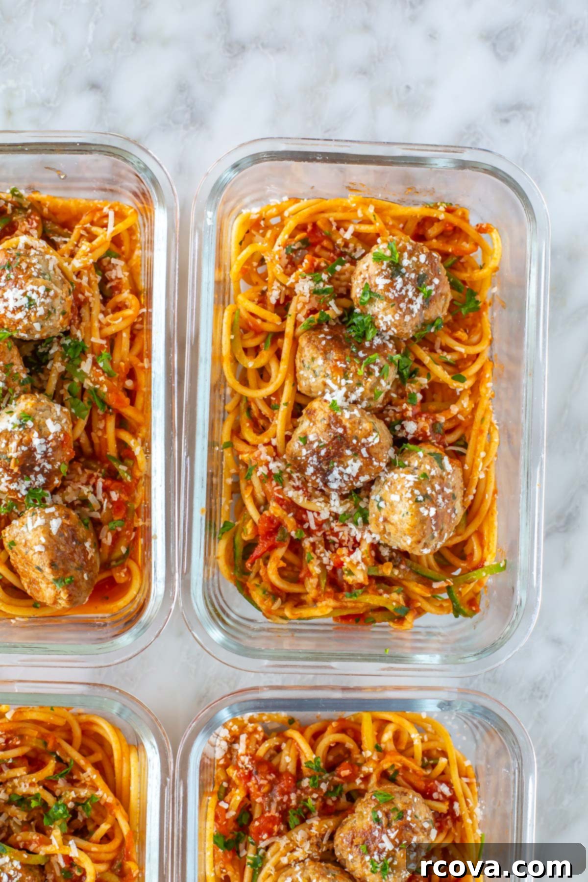 Effortless Oven Baked Turkey Meatballs 4 A close-up of baked turkey meatballs in a meal prep container with pasta and zucchini noodles.