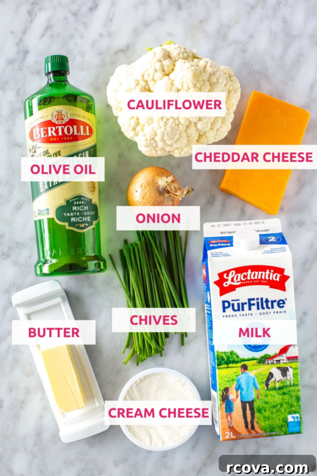 Decadent Low Carb Cauliflower Mac and Cheese 4 A vibrant flat lay of fresh ingredients for low-carb cauliflower mac and cheese: olive oil, a head of cauliflower, a block of cheddar cheese, a carton of milk, a yellow onion, a bunch of chives, a stick of butter, and a tub of cream cheese.