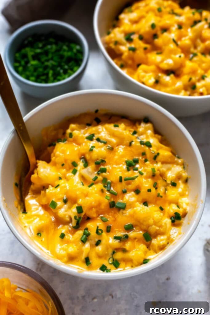 Decadent Low Carb Cauliflower Mac and Cheese 7 A close-up shot of creamy Cauliflower Mac and Cheese in a white bowl, garnished with green herbs, emphasizing its comforting and healthy appeal.