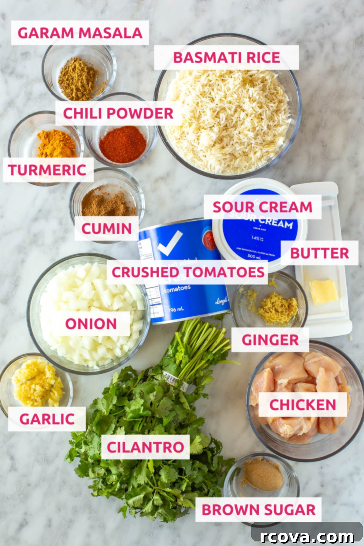 Creamy Slow Cooker Chicken Tikka Masala 3 Various ingredients laid out for slow cooker chicken tikka masala, including chicken, brown sugar, cilantro, ginger, garlic, onion, crushed tomatoes, sour cream, butter, cumin, turmeric, chili powder, garam masala, and basmati rice.
