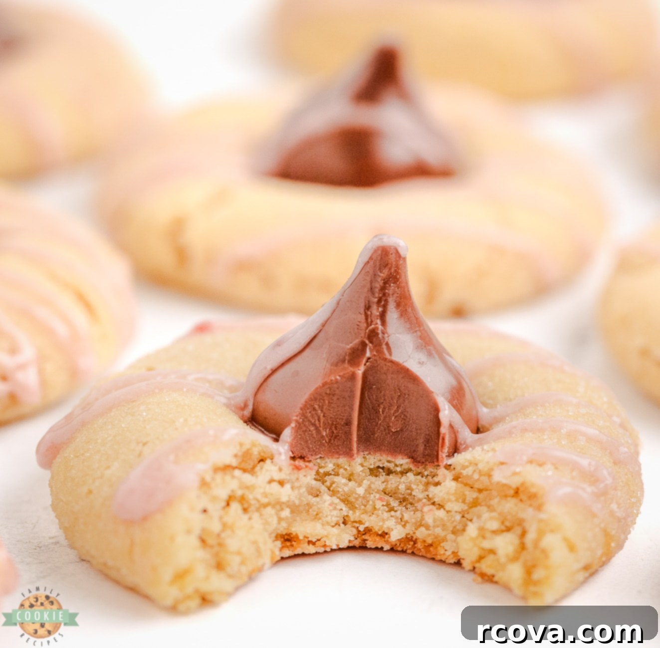 Luscious Raspberry Almond Kiss Cookies 2 Raspberry almond kiss cookies with a bite taken out, showing the soft interior and chocolate kiss.