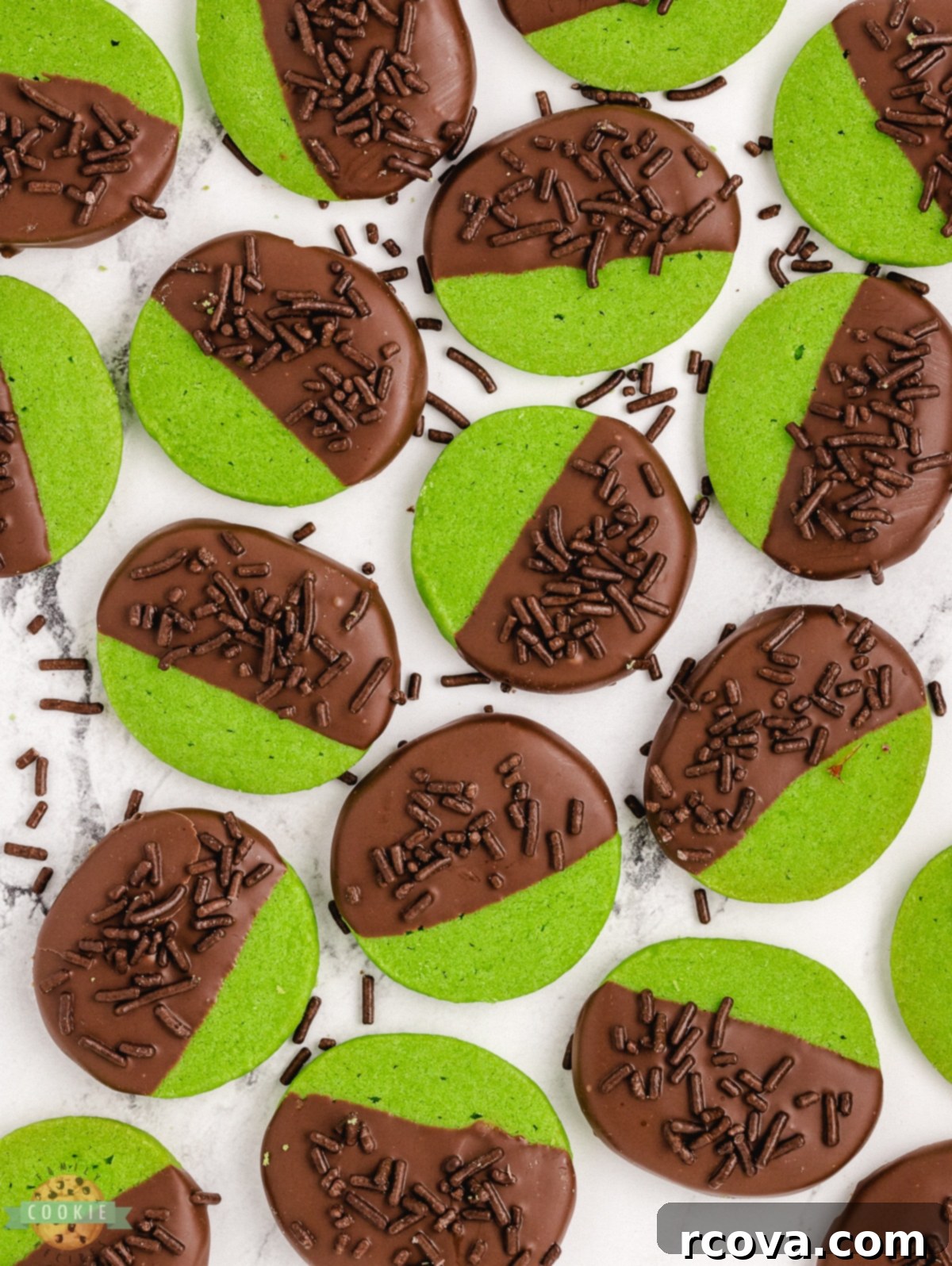 Ultimate Chocolate Mint Cookies 5 Green mint shortbread cookies partially dipped in dark chocolate and topped with chocolate sprinkles, showcased on a white surface.