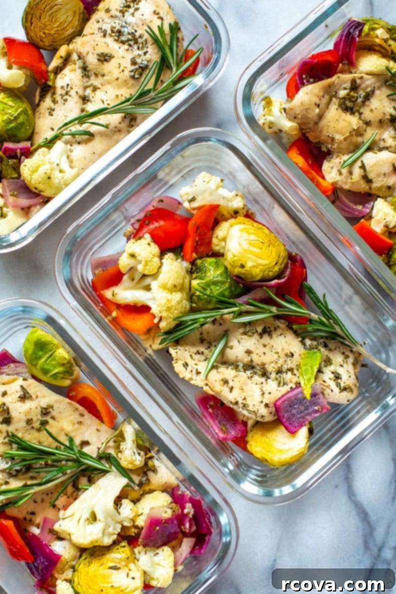 Our Sheet Pan Rosemary Chicken is a healthy, low-carb chicken meal prep recipe. It's perfect as a 30-minute dinner or to pack up as weekly lunch bowls!  Raw boneless, skinless chicken breasts seasoned with fresh rosemary, garlic, and lemon, alongside colorful chopped vegetables on a baking sheet, ready for the oven.