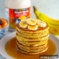 Effortless Two Ingredient Banana Egg Pancakes 10 A stack of banana egg pancakes with extra banana slices and maple syrup on top.