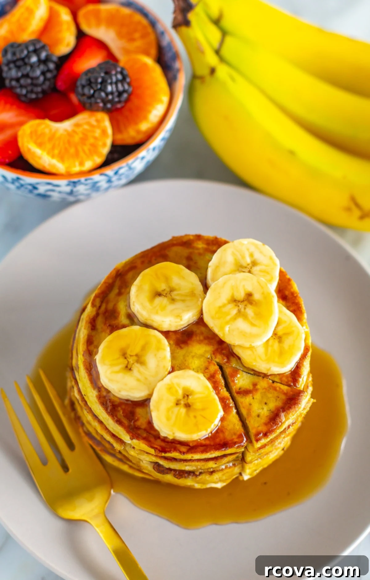 Effortless Two Ingredient Banana Egg Pancakes 8 An overhead shot of banana egg pancakes with a bowl of fruit next to it.