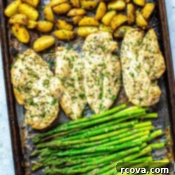 Golden Chicken and Asparagus Roast 9 A sheet pan with roasted potatoes, seasoned chicken breasts, and asparagus on top.