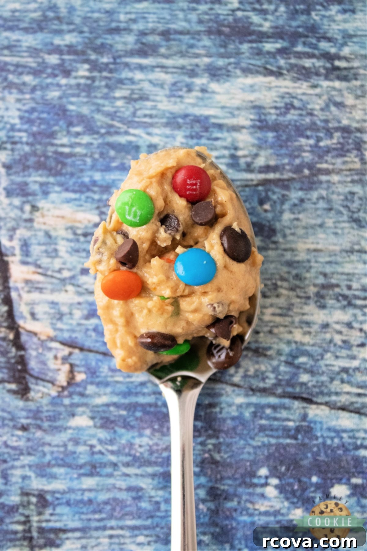 No-Bake Monster Cookie Dough 3 Close-up of a spoonful of creamy edible cookie dough, showing peanut butter, oats, and colorful M&Ms.