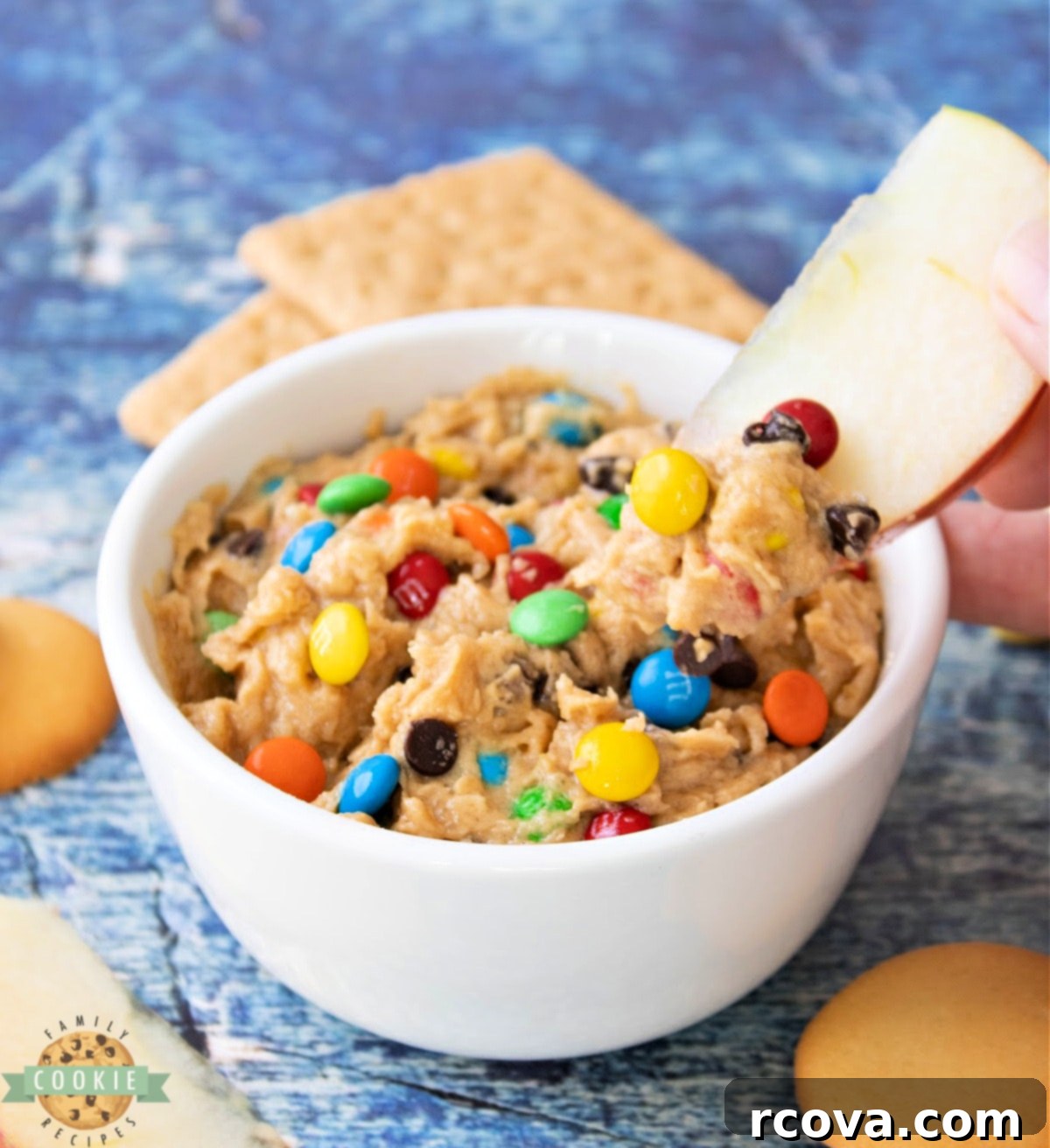 No-Bake Monster Cookie Dough 5 A serving bowl filled with Edible Monster Cookie Dough, surrounded by pretzels, graham crackers, and apple slices, perfect for dipping.
