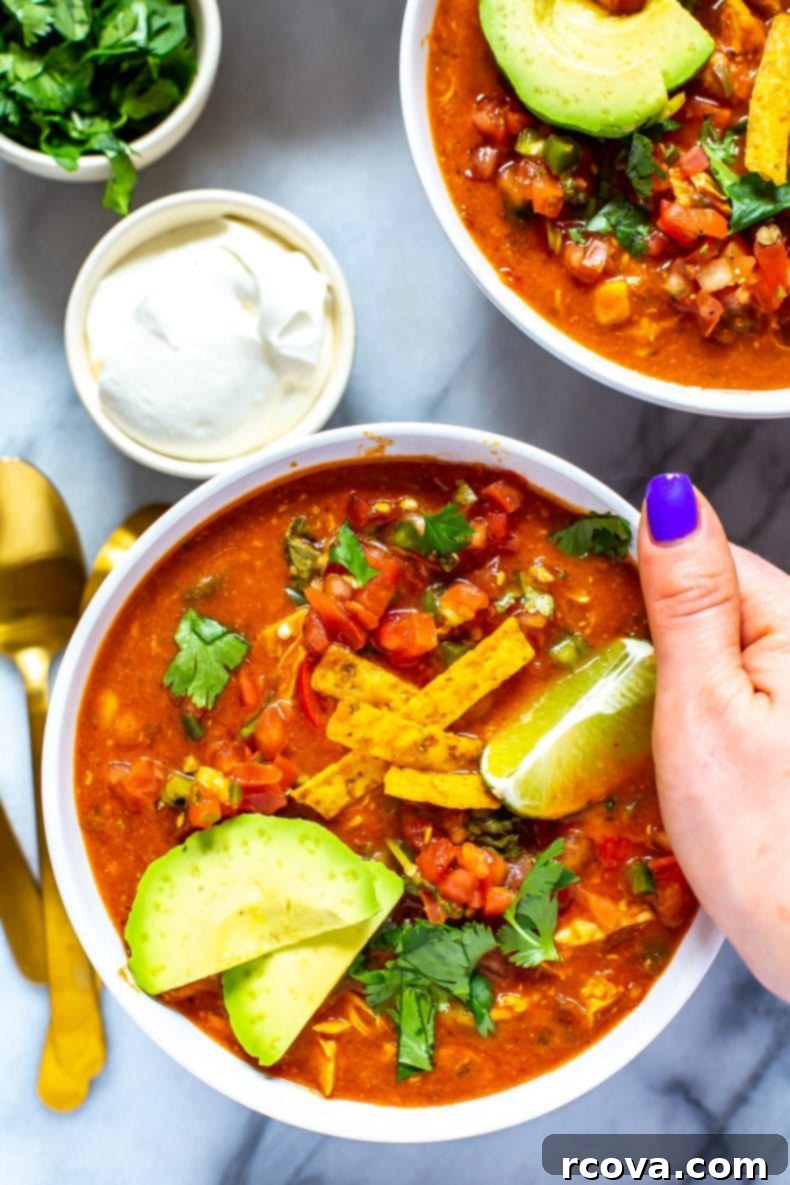 This Instant Pot Chicken Enchilada Soup is a delicious copycat of Chili's enchilada soup recipe. It's made healthier and easily using pantry staples! You'll love this Mexican soup!  woman with purple nail polish holding bowl of chicken enchilada soup