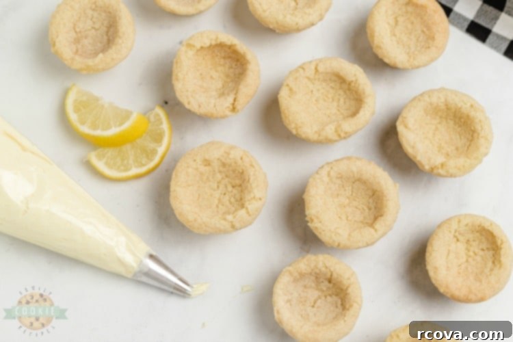 Zesty Lemon Cloud Cookies 7 A mini muffin tin filled with freshly baked Lemon Cream Pie Cookies, each with a perfect indentation in the center, ready to be filled.