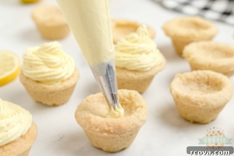 Zesty Lemon Cloud Cookies 8 Two hands meticulously piping creamy lemon filling into golden cookie cups from a pastry bag, illustrating the final assembly step for Lemon Cream Pie Cookies.