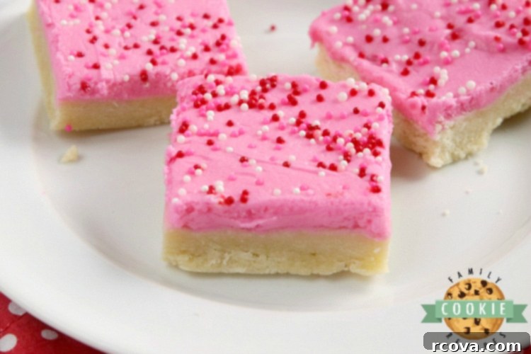 Delicious Sugar Cookie Bars 7 Close-up of sugar cookie bars with festive sprinkles on top, neatly arranged on a white plate after being cut.