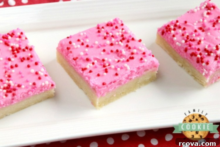 Delicious Sugar Cookie Bars 8 Stacked sugar cookie bars, frosted and decorated with sprinkles, presented on a white plate, emphasizing their soft texture and appealing appearance.