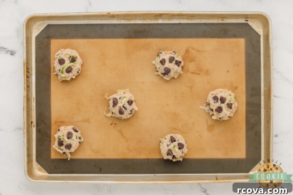 Hidden Veggie Chocolate Chip Delights 9 Scoops of Zucchini Chocolate Chip Cookie dough neatly placed on a greased cookie sheet, ready for baking.