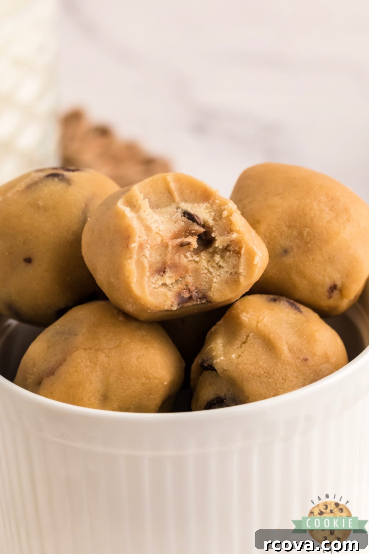 Indulgent Chocolate Chip Dough Gems 3 A bowl filled with many edible chocolate chip cookie dough balls, showcasing their perfectly round shape.