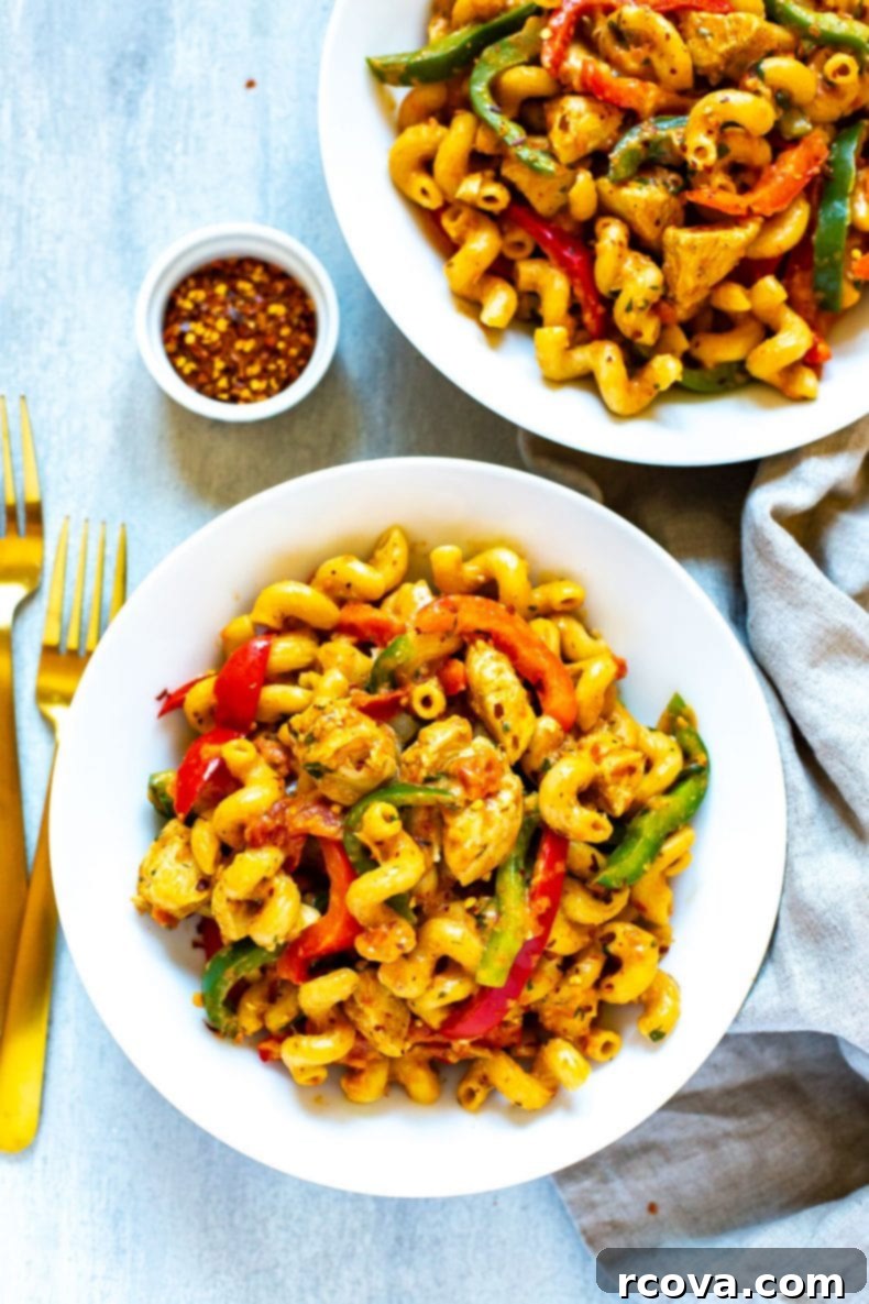 Delicious One-Pot Cajun Chicken Pasta with chicken, bell peppers, and creamy sauce Close-up shot of a serving of creamy Cajun chicken pasta in a bowl, with a fork digging in.