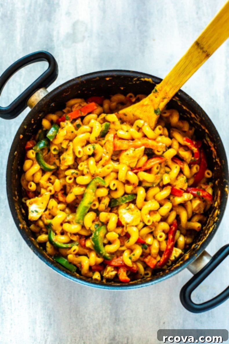 Cooking a delicious one-pot pasta for an easy dinner. Overhead view of a one-pot pasta dinner being stirred, featuring pasta, chicken, and bell peppers in a rich sauce.