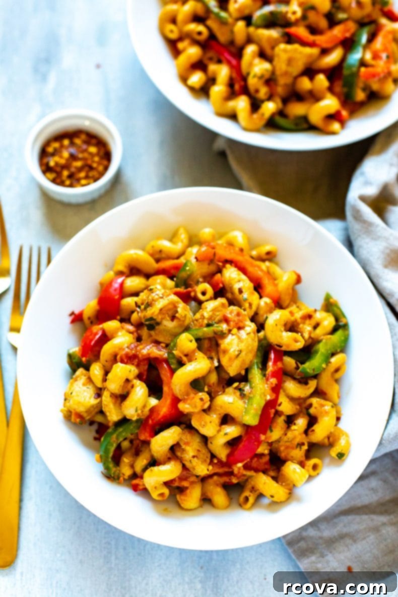 Enjoy this spicy chicken, vegetables, and Cavatappi pasta in a bowl. A bowl of spicy Cajun chicken pasta with cavatappi noodles and various vegetables, ready to eat.