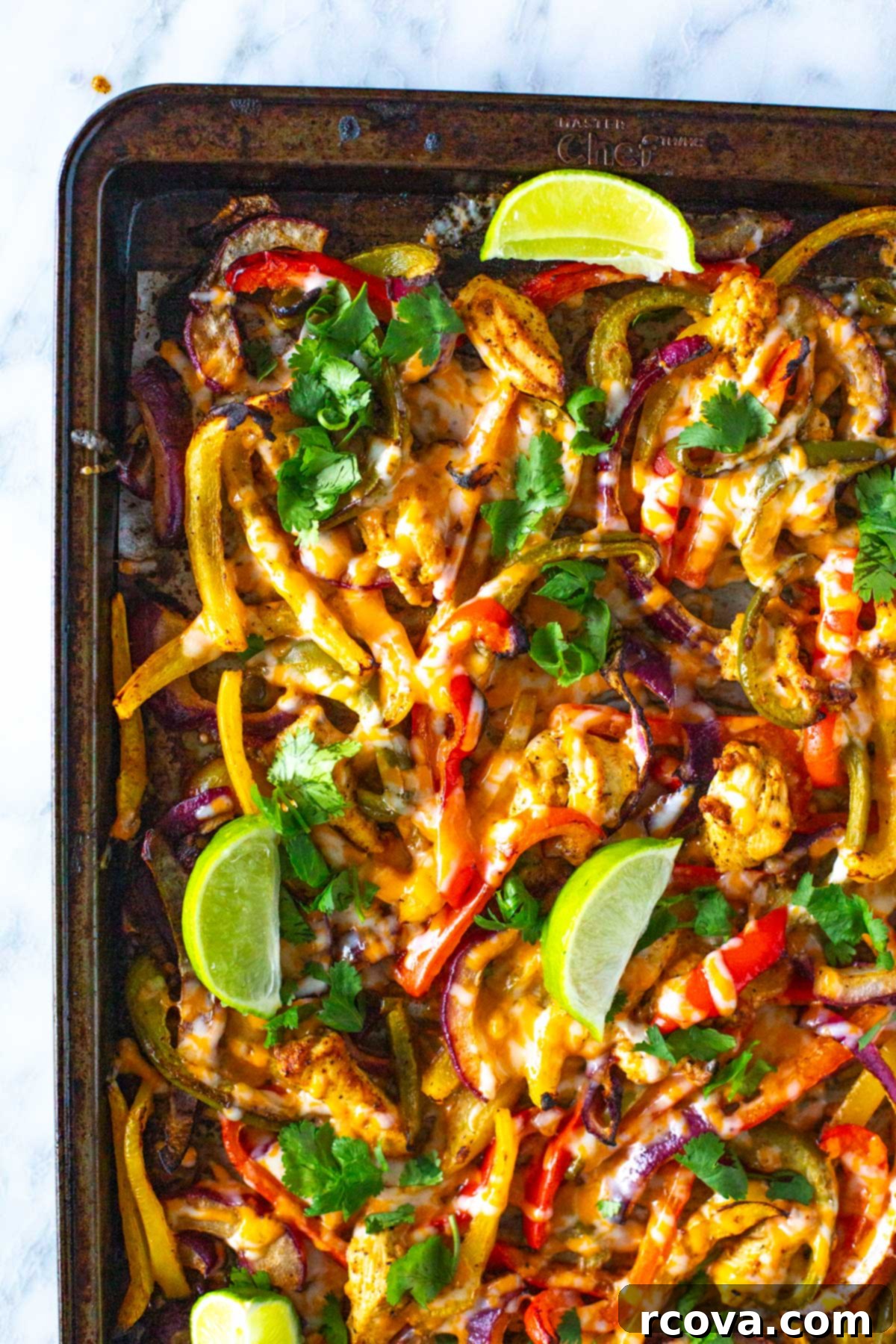 These Sheet Pan Chicken Fajitas are a quick and easy way to enjoy your Tex Mex favorite. This chicken fajita recipe comes together on one pan in 30 minutes! Close-up of vibrant sheet pan chicken fajitas served in warm corn tortillas, garnished with fresh cilantro and lime wedges.