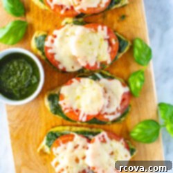 One-Pan Pesto Chicken Bake 11 Four chicken cutlets on a butcher block topped with pesto, tomato and mozzarella cheese, ready for a delicious meal.