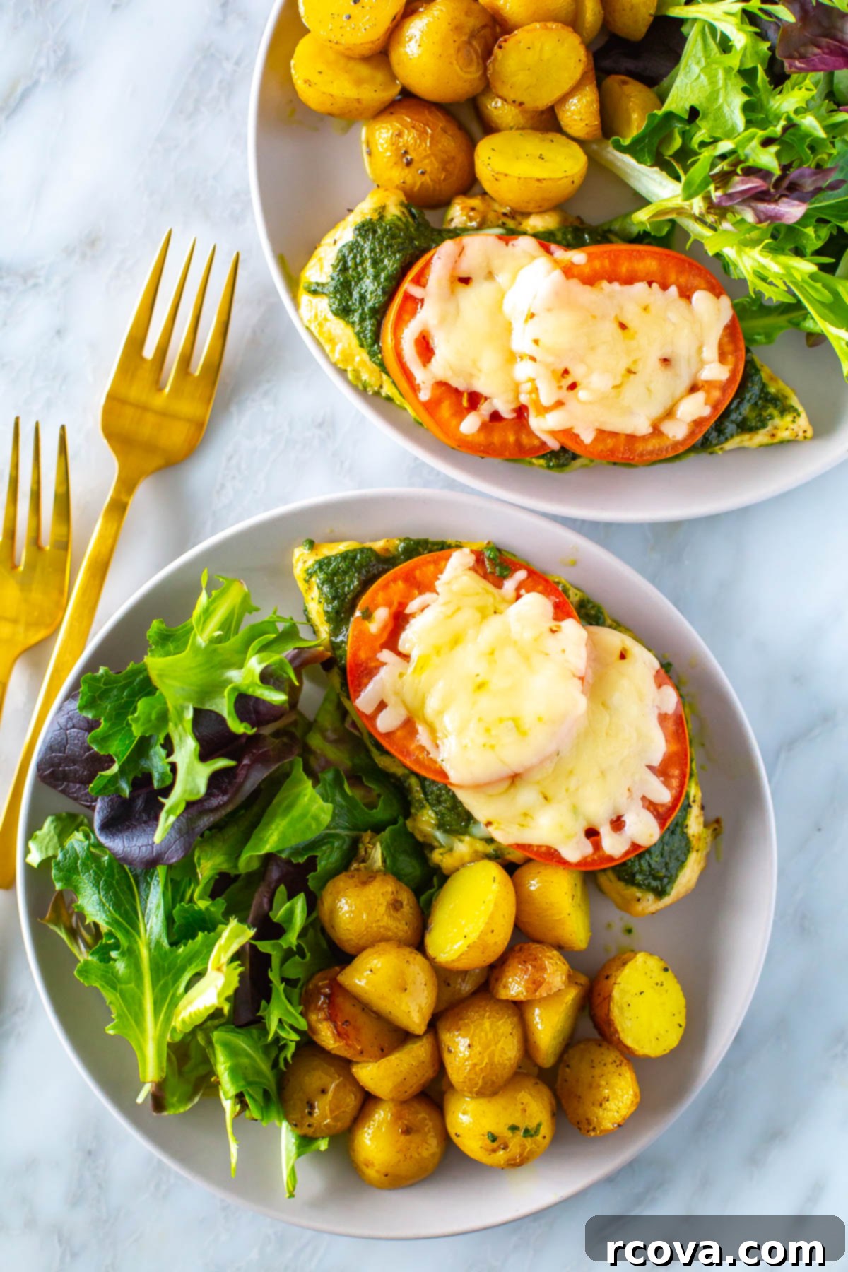 One-Pan Pesto Chicken Bake 7 Two plates, each with pesto chicken and a side of roasted potatoes and fresh salad, highlighting a complete meal.