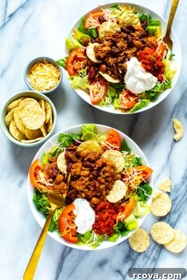 Enjoy a homemade Wendy's Taco Salad, featuring a delicious and freezer-friendly chili recipe, perfect for any meal, and easily customizable! Two bowls of chili taco salad surrounded by tortilla chips, ready to be enjoyed.