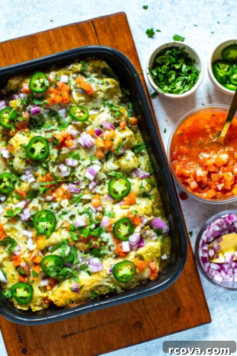 This easy and flavorful Chicken Enchiladas Verdes recipe, made with a bright tomatillo-based salsa verde, serves as a fantastic dinner casserole and an even better meal prep option! #greenenchiladas #enchiladasverdes #chickenmealprep Delicious Meal Prep Chicken Enchiladas Verdes in a baking dish, garnished with fresh cilantro and jalapeños.
