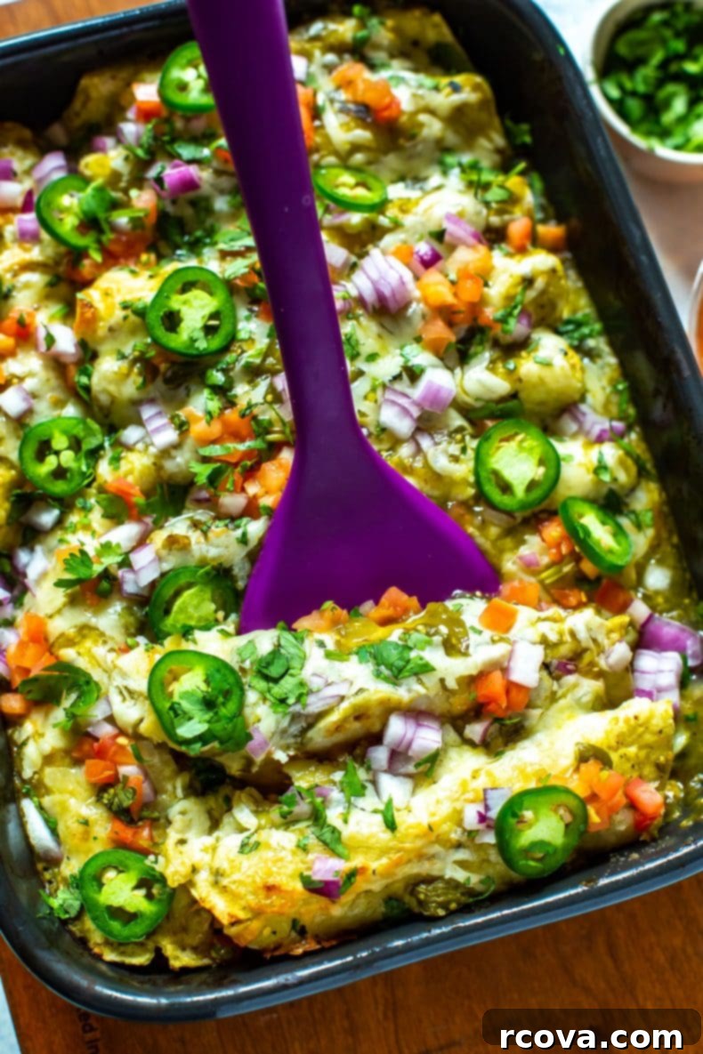 This Chicken Enchiladas Verdes recipe is made with tomatillo-based salsa verde and comes together as an easy dinner casserole - it also works great as flavorful meal prep lunches! #greenenchiladas #enchiladasverdes #chicken Serving freshly baked chicken enchiladas verdes directly from the casserole dish, showing the cheesy, saucy goodness.