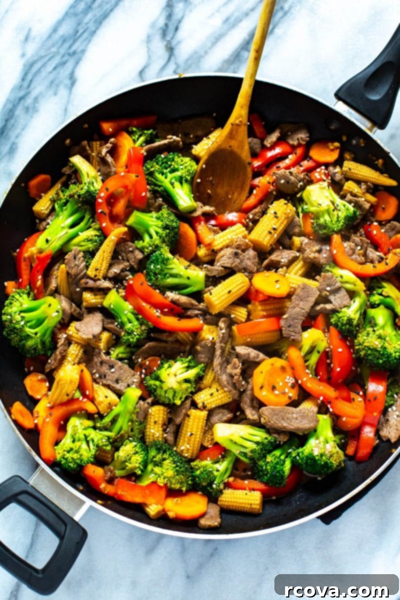This is the EASIEST Beef Stir Fry recipe out there - with a simple 2-ingredient sauce, you'll likely already have all the ingredients you need to make this healthy dinner idea! #beefstirfry #skilletrecipe Close-up of a sizzling beef stir fry with vibrant vegetables and tender beef, ready in 30 minutes