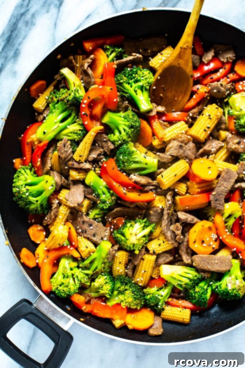 This is the EASIEST Beef Stir Fry recipe out there - with a simple 2-ingredient sauce, you'll likely already have all the ingredients you need to make this healthy dinner idea! #beefstirfry #skilletrecipe Close-up of beef and broccoli stir fry sizzling in a black skillet, perfectly cooked