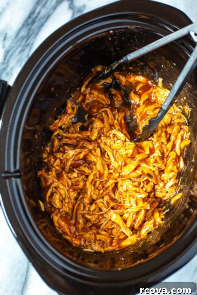 Effortless 2-Ingredient Slow Cooker BBQ Chicken 6 A stack of three BBQ chicken sliders with kale slaw on the side, ready to eat.