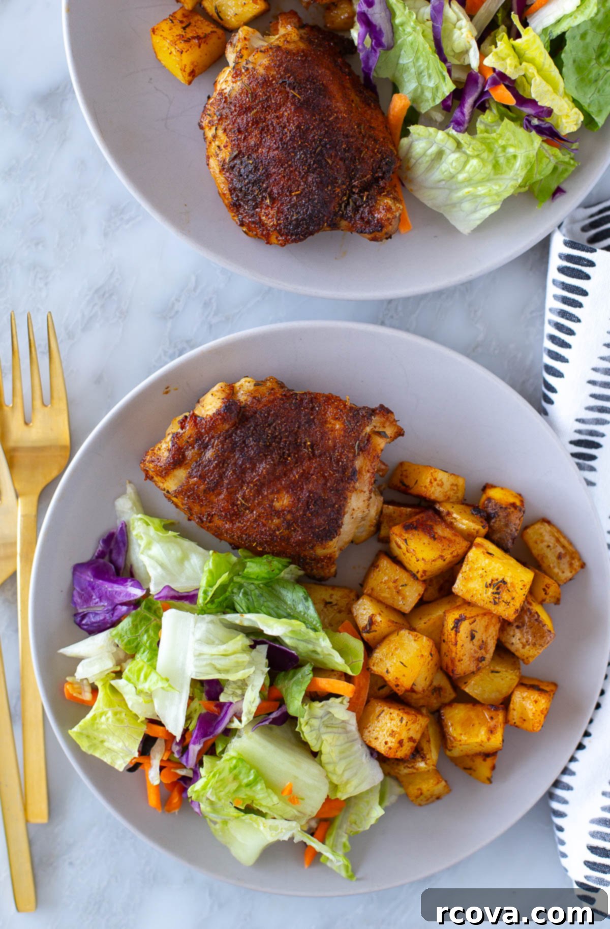 Succulent Baked Chicken Thighs with Crispy Skin 9 Overhead shot of baked chicken thighs plated with salad and roasted potatoes, glistening and perfectly cooked.