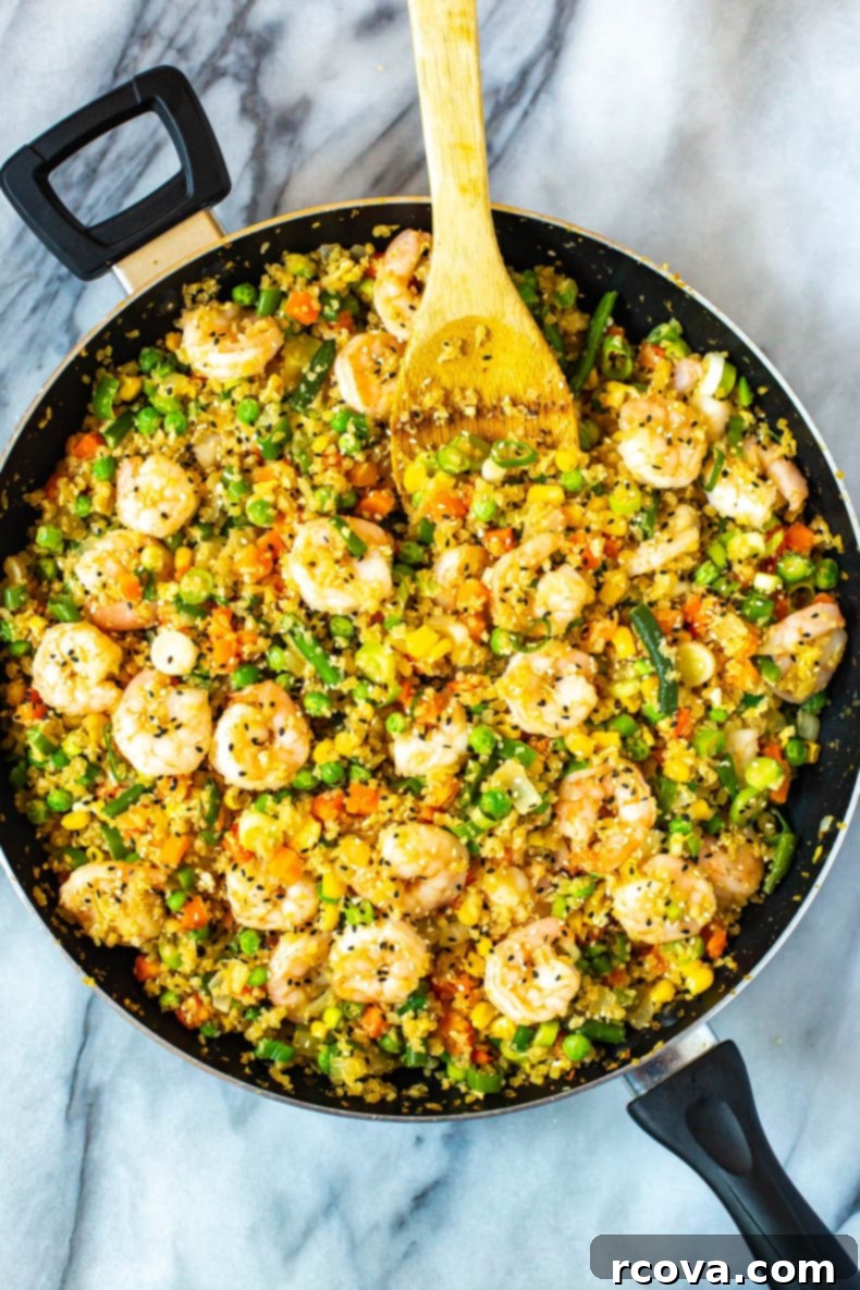 Ultimate Low Carb Cauliflower Fried Rice 2 A vibrant bowl of The Best Cauliflower Fried Rice with plump shrimp, colorful vegetables, and a sprinkle of green onions and sesame seeds, ready to be enjoyed as a low-carb, healthy meal.