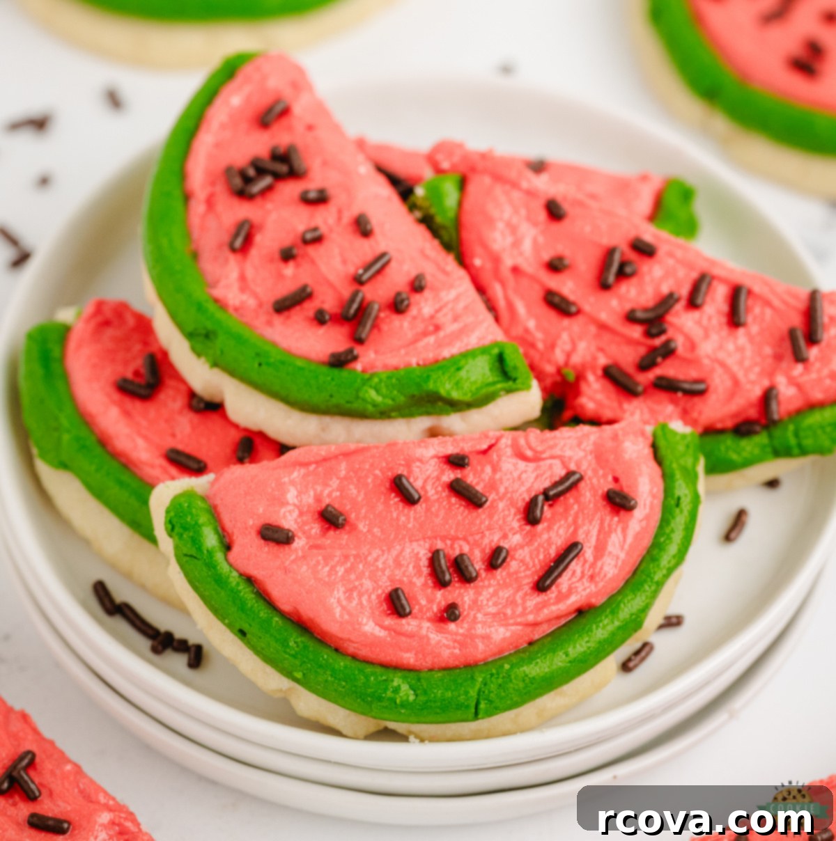 Summer Kissed Watermelon Cookies 2 plate of frosted watermelon cookies, showcasing their vibrant pink and green frosting and chocolate seed details
