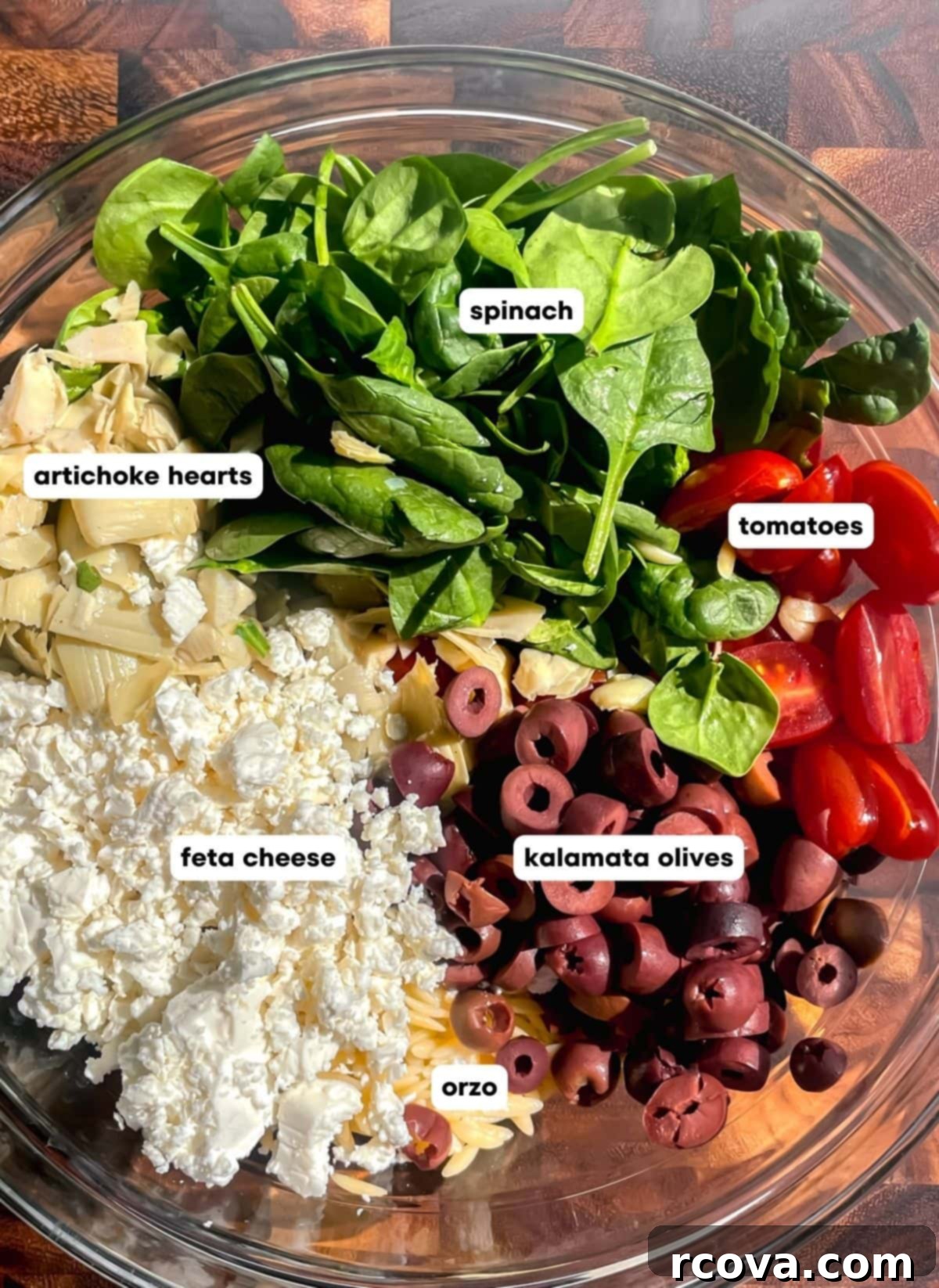 Zesty Greek Orzo Salad with Lemon-Herb Vinaigrette 3 Close-up of fresh Mediterranean Greek Orzo Salad ingredients, showcasing cherry tomatoes, crumbled feta, sliced Kalamata olives, and tender orzo pasta before mixing.