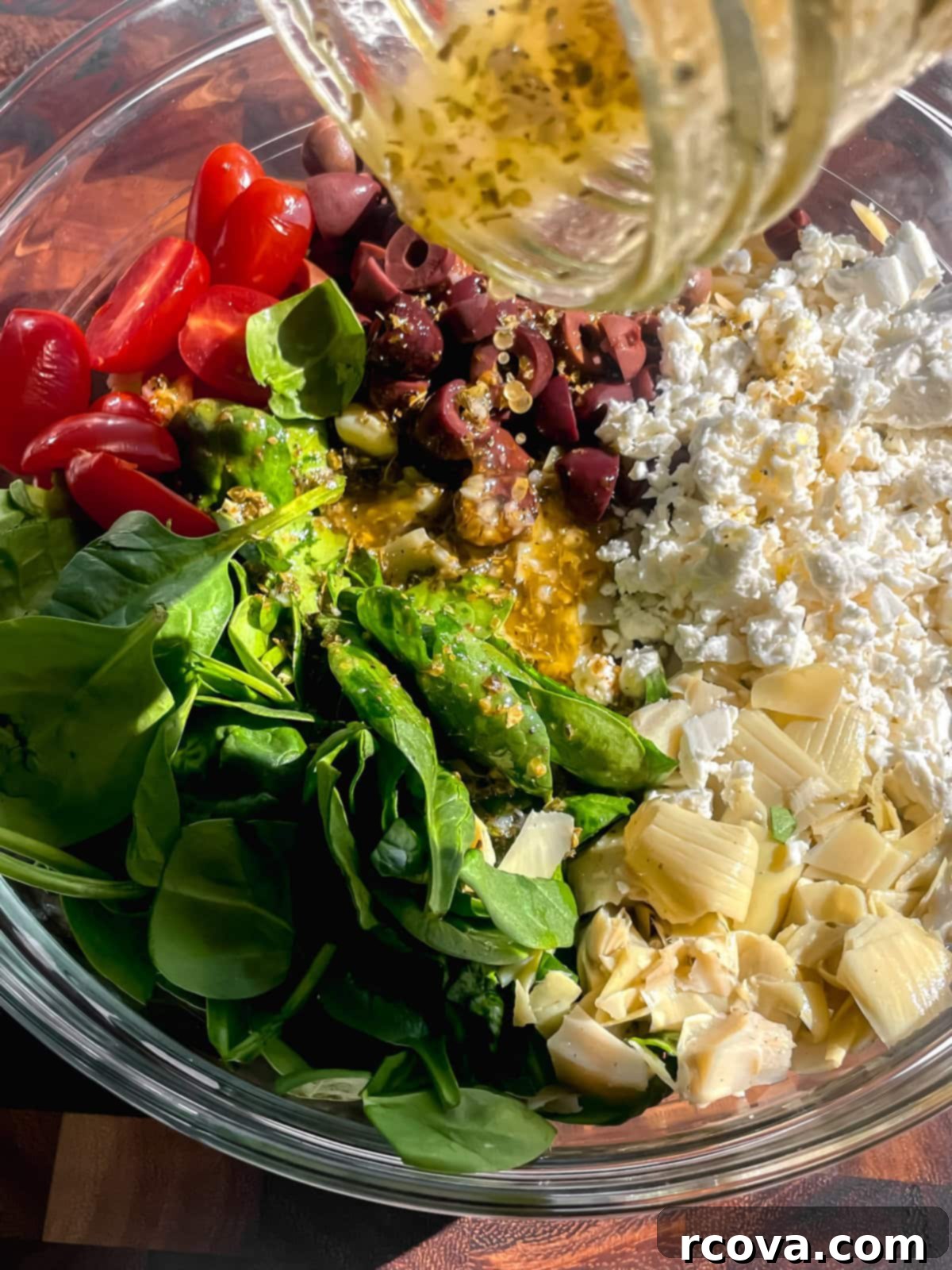 Zesty Greek Orzo Salad with Lemon-Herb Vinaigrette 4 Hand pouring homemade Greek Lemon Vinaigrette generously over a large bowl of Mediterranean Greek Orzo Salad ingredients, ready for tossing.