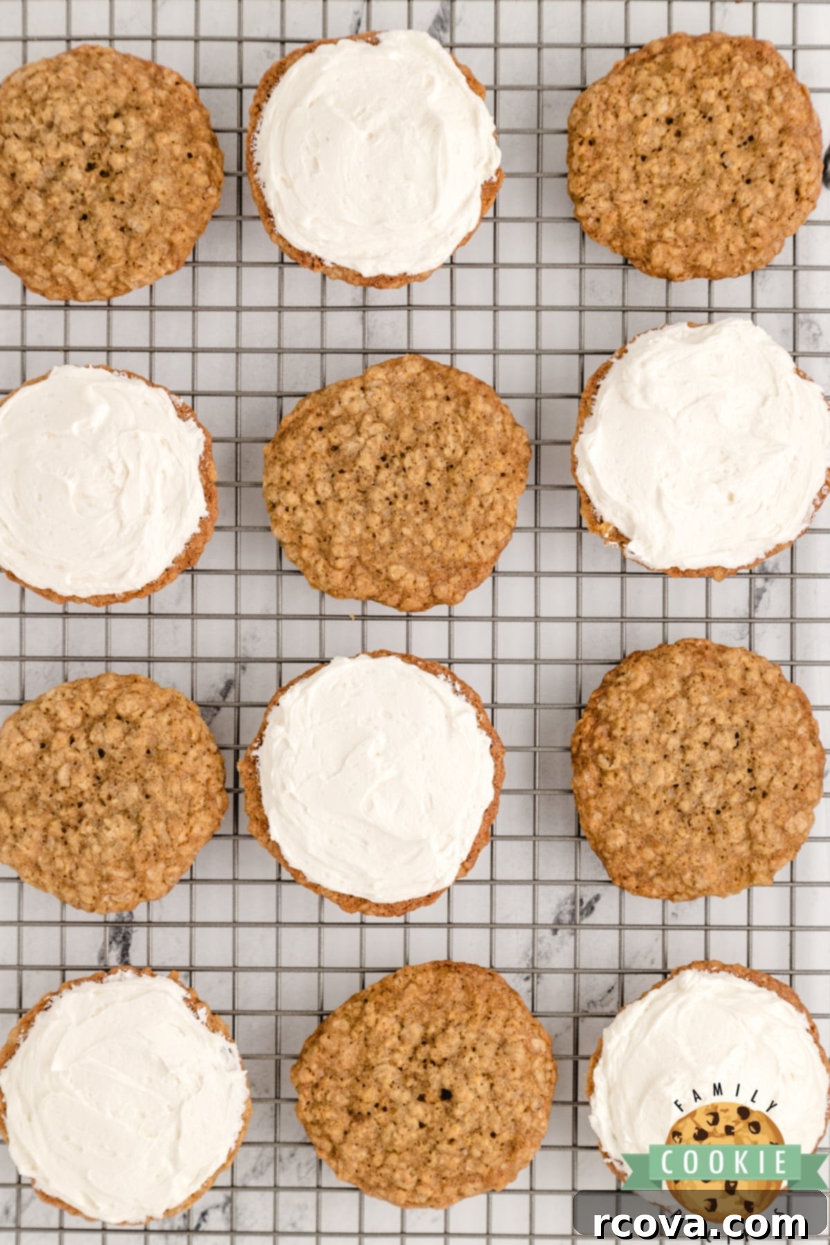 Dreamy Oatmeal Cream Cookies 9 A hand placing the top oatmeal cookie onto a dollop of marshmallow buttercream filling on another cookie, forming a sandwich