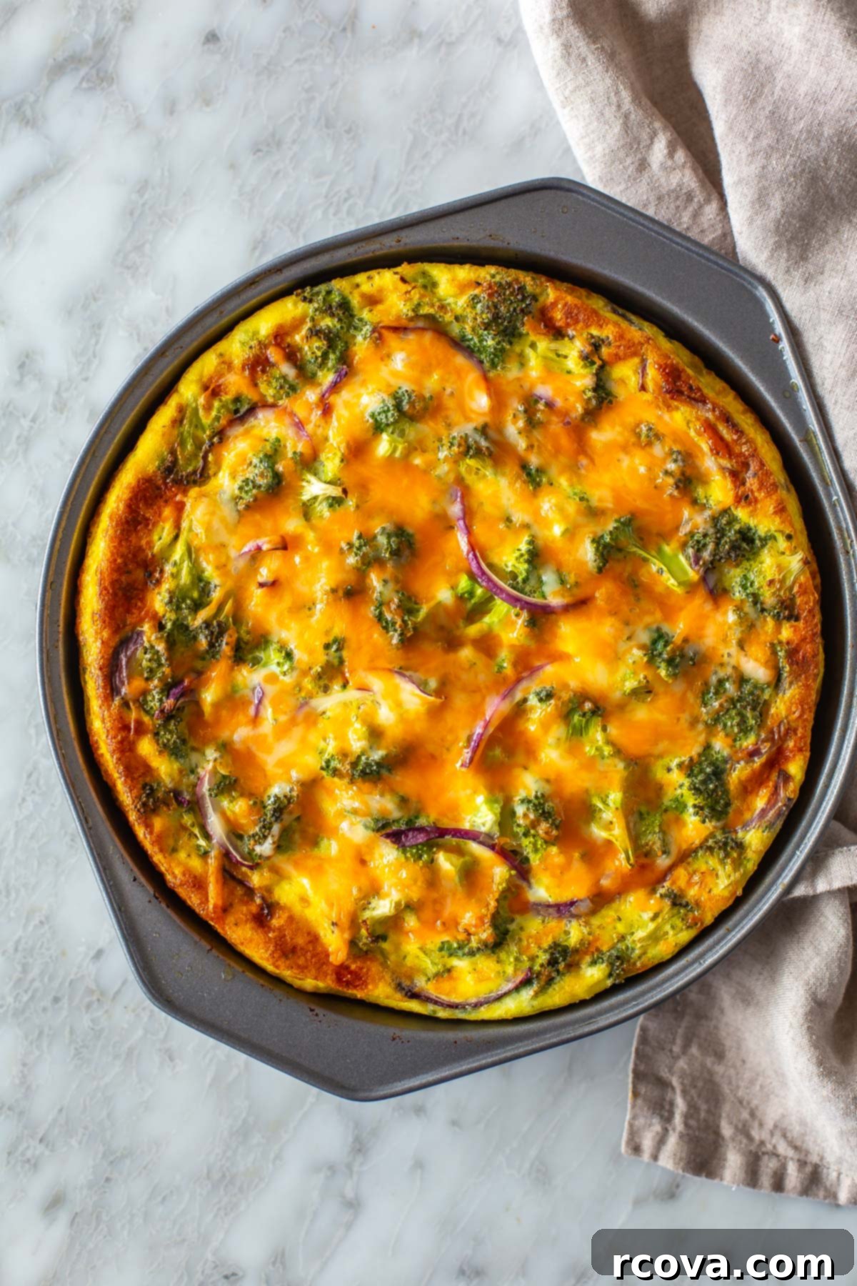 Low Carb Crustless Broccoli Cheddar Quiche 10 A large slice of Crustless Broccoli Cheddar Quiche on a white plate, ready to be served.