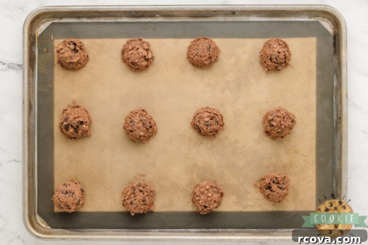 Decadent Double Chocolate Oatmeal Delights 6 Double chocolate oatmeal cookie dough scooped onto a cookie sheet.