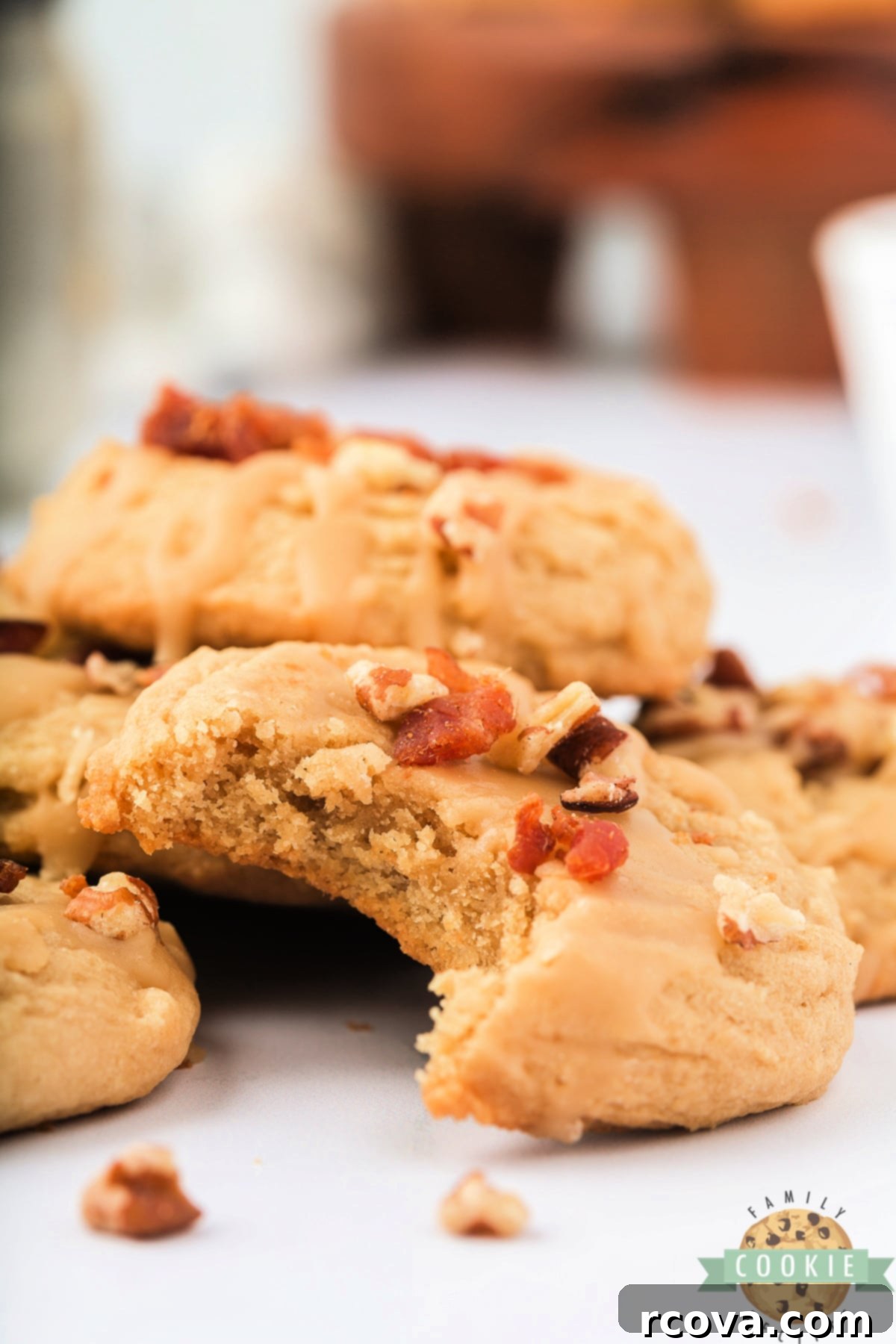 Sweet & Savory Maple Bacon Cookies 13 A stack of beautifully glazed Maple Bacon Cookies, some with nuts and bacon bits, arranged on a rustic wooden surface, highlighting their homemade appeal.