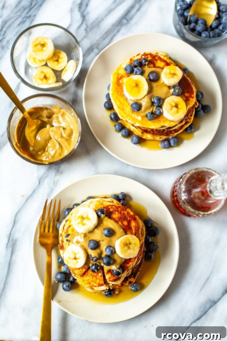 Power-Packed 4-Ingredient Fluffy Pancakes 8 Stack of fluffy protein pancakes drizzled with syrup and topped with fresh berries on a white plate.