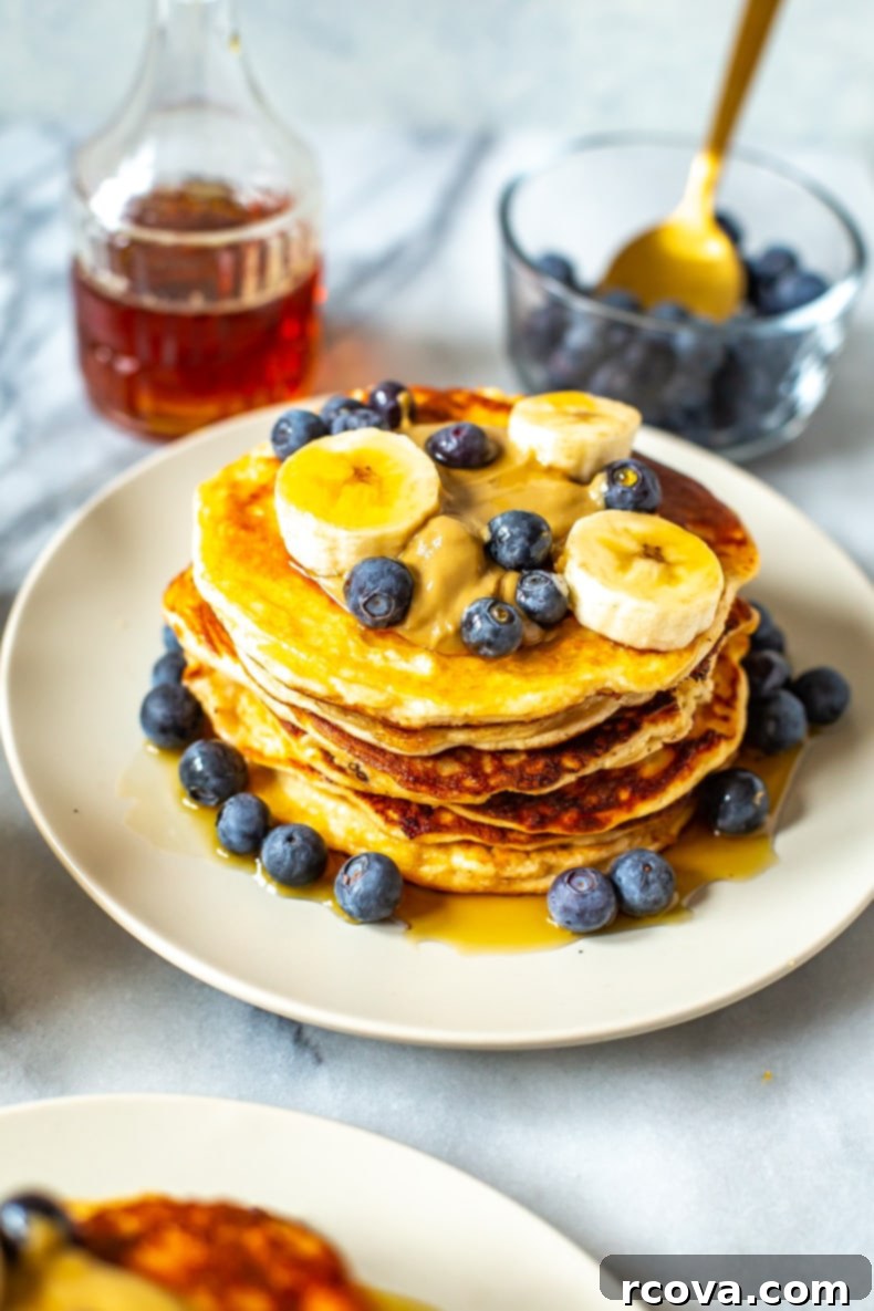 Power-Packed 4-Ingredient Fluffy Pancakes 9 Close-up of golden protein pancakes with fresh blueberries and a fork.