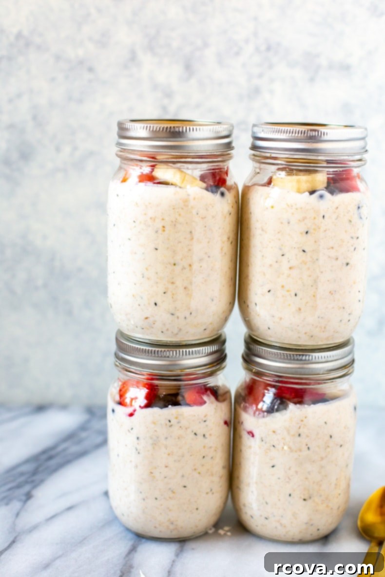 Effortless Morning Oats 7 Stack of mason jars filled with overnight steel cut oats, topped with vibrant fresh fruit and mint.